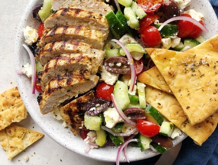 salade à la grecque avec du pain plat poulet tomates concombre oignon poivron et fromage feta