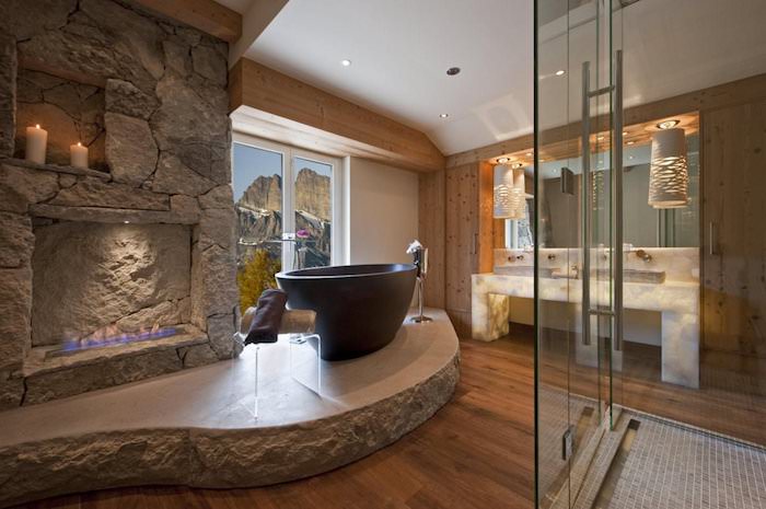 salle de bain de luxe avec cheminée et bougies baignoire en pierre plancher en bois
