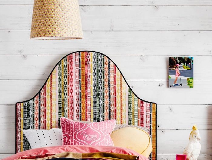 tete de lit tissu multicolore sur un mur en planches de bois blanches coussins et couvertures en couleurs différentes