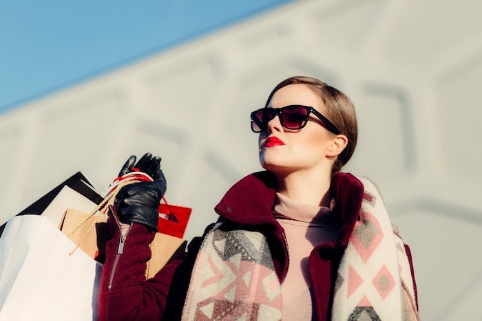 une femme avex lunettes de soleil rouge a levre rouge shopping bags