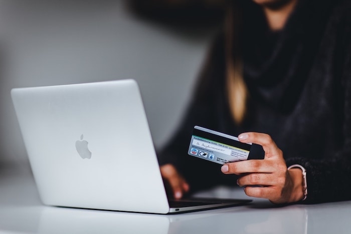 une femme qui tiens dans ses mains carte bancaire shopping online