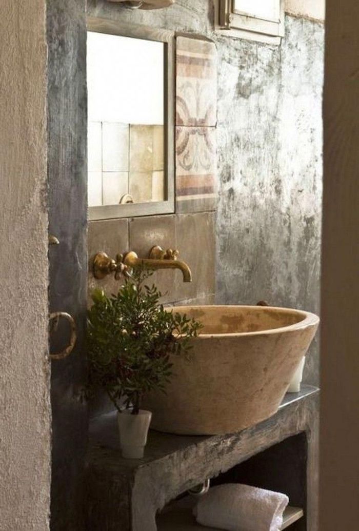 vasque en pierre des accents laiton murs en travertin plante dans la salle de bain