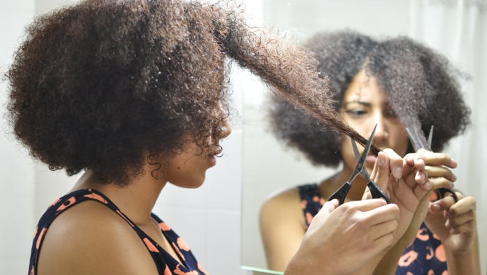 coiffure cheveux bouclés une fille qui coupe ses cheveux bouclés à sec avec des ciseaux resized