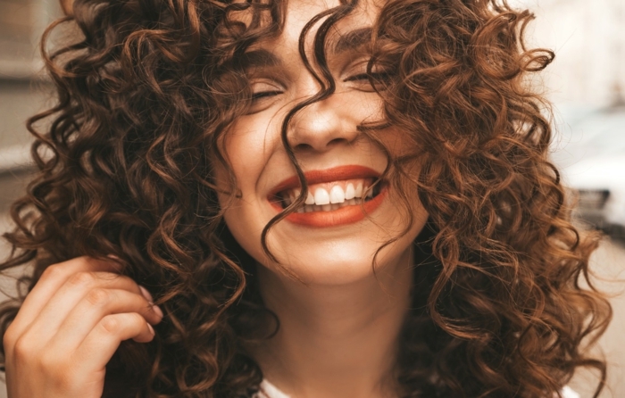 coiffure cheveux bouclés femme avec des cheveux bouclés qui sourit resized