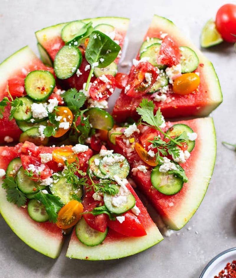 tranches de pasteque garnies de tomates concombre persil miettes de fromage