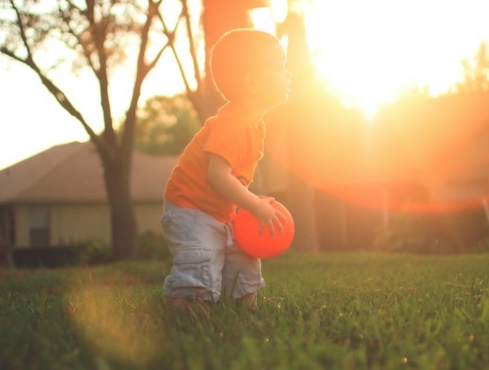 bebe de 2 ans qui joue sur une pelouse verte couche de soleil