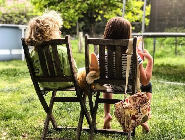 deux enfants assis sur deux chaises dans le jardin