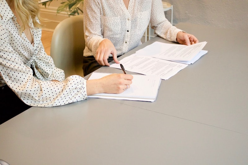 deux femmes en train de signer des documents