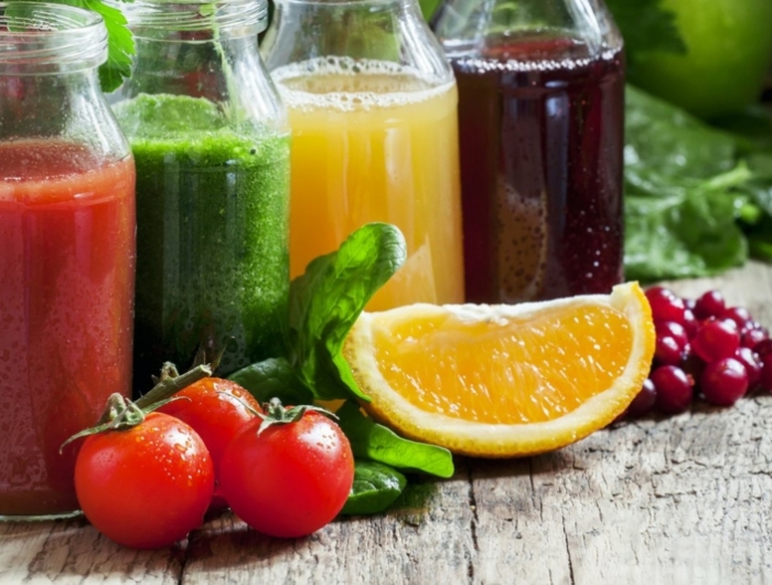 bottles with fresh juices from fruits and vegetables on an old w