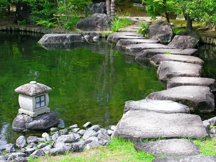 jardin zen japonais grand bassin avec mousse sentier tordu en pierre petite lanterne japonaise