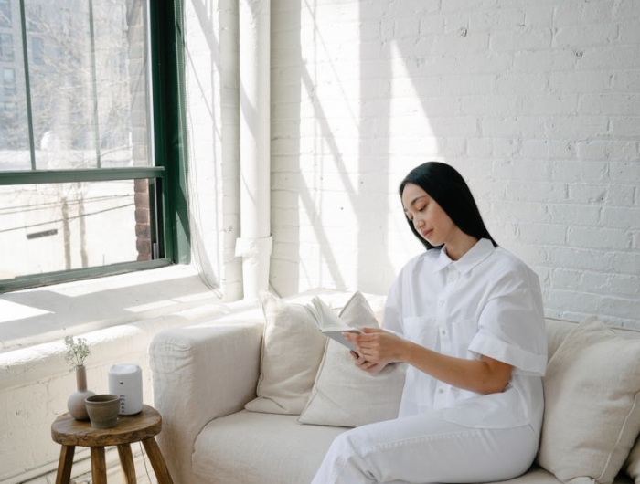 assurance habitation pas cher femme en blanc sur canapé blanc mur en briques
