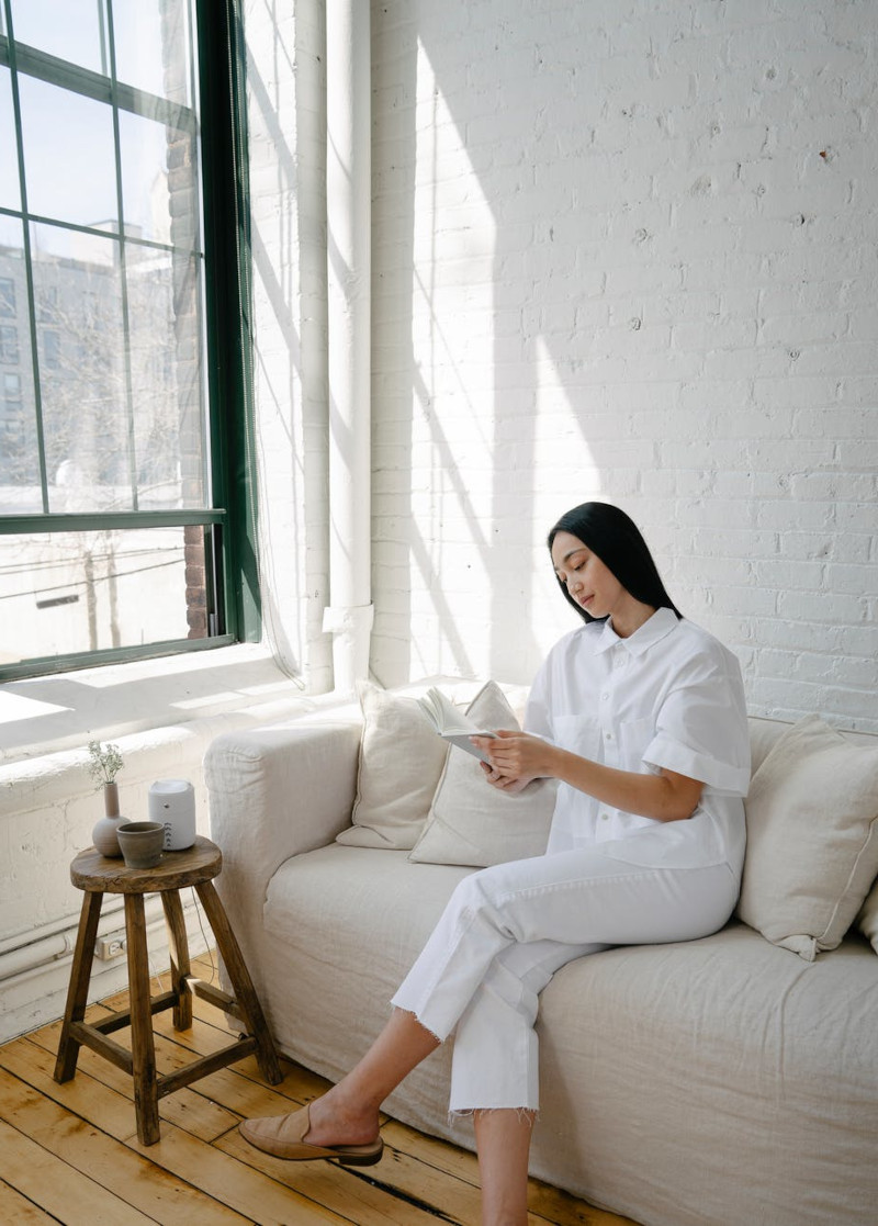 assurance habitation pas cher femme en blanc sur canapé blanc mur en briques