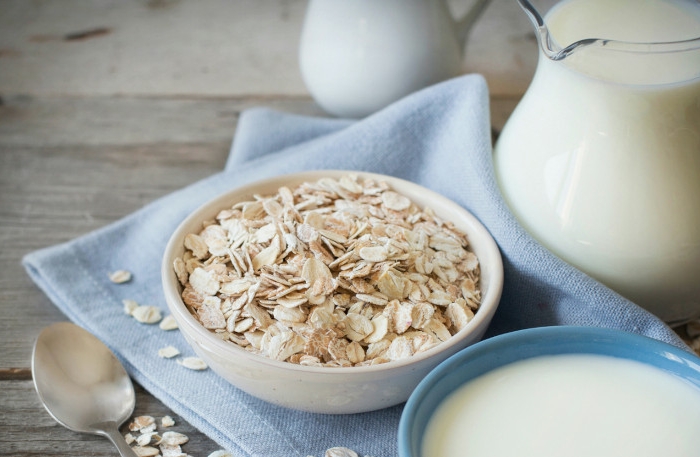 rolled oats in a bowl and milk on a wooden table