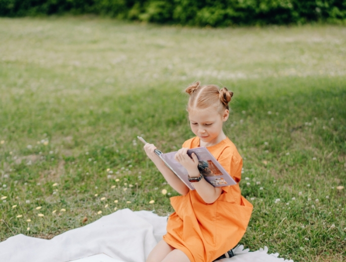 cendre dans le jardin une petite fille qui lit un livre sur la pelouse