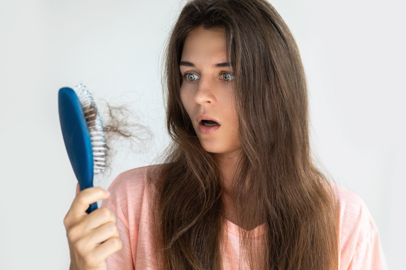 comment laver une brosse à cheveux une femme qui regarde étonnée sa brosse