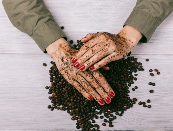 women's hands with red nail polish applied the coffee scrub