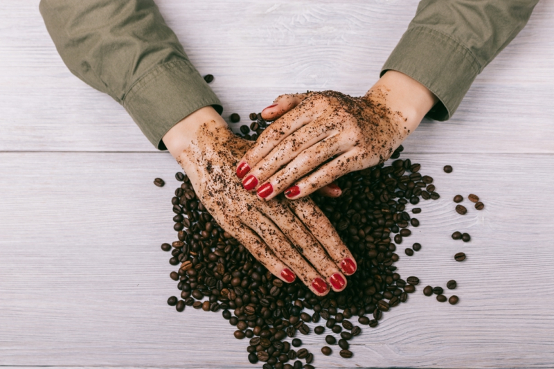 women's hands with red nail polish applied the coffee scrub