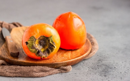 pomme kaki deux fruits mûrs en orange vif sur une planche en bois