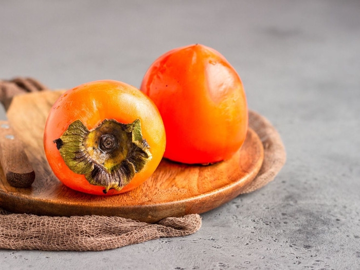 pomme kaki deux fruits mûrs en orange vif sur une planche en bois
