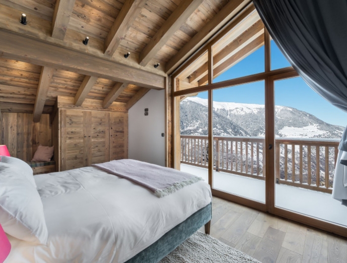 chambre chalet linge de lit blanc murs en bois portes fenetres avec vus splendide