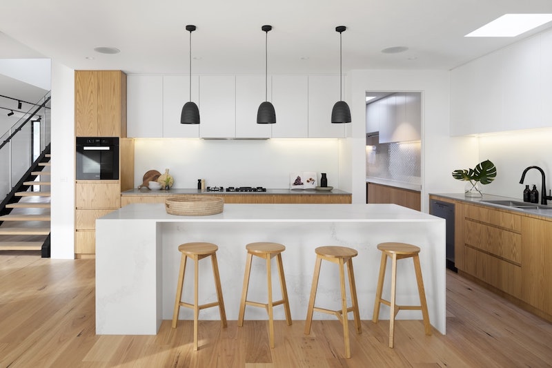 white and blond wooden kitchen with white island wooden base units parquet floor black floor lamps