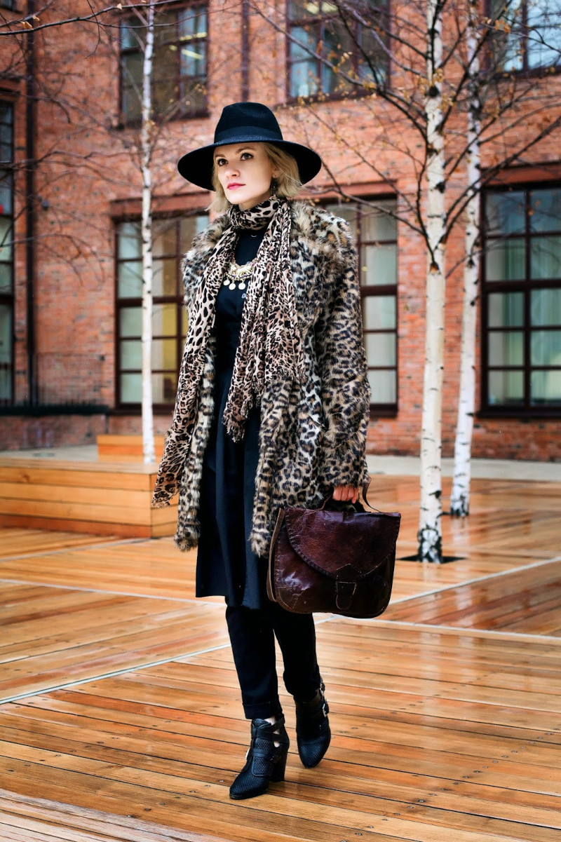 manteau léopard femme à la tenue chic en noire chapeau à bords noir bottines noires
