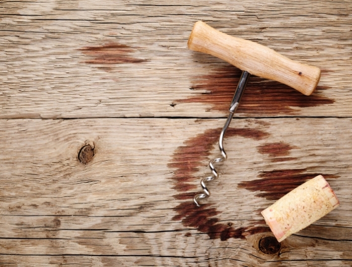 corkscrew, cork and wine stains on wooden background