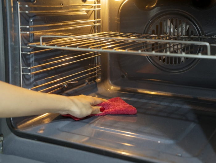 cropped hand of woman cleaning oven