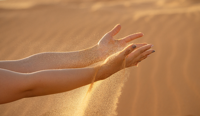 peau très sèche deux mains qui dispersent du sable dans le desert