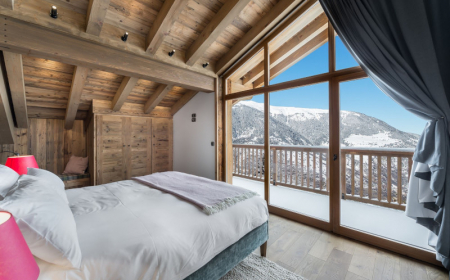 chambre chalet linge de lit blanc murs en bois portes fenetres avec vus splendide