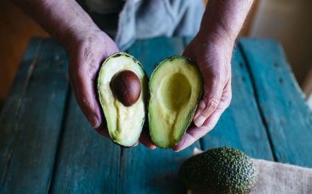 hands holding two halves of an avocado