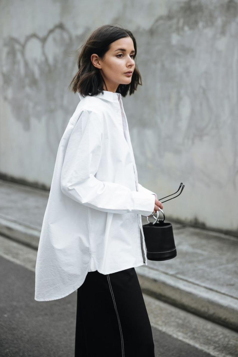 Short haircut woman in an oversized white blouse with black pants