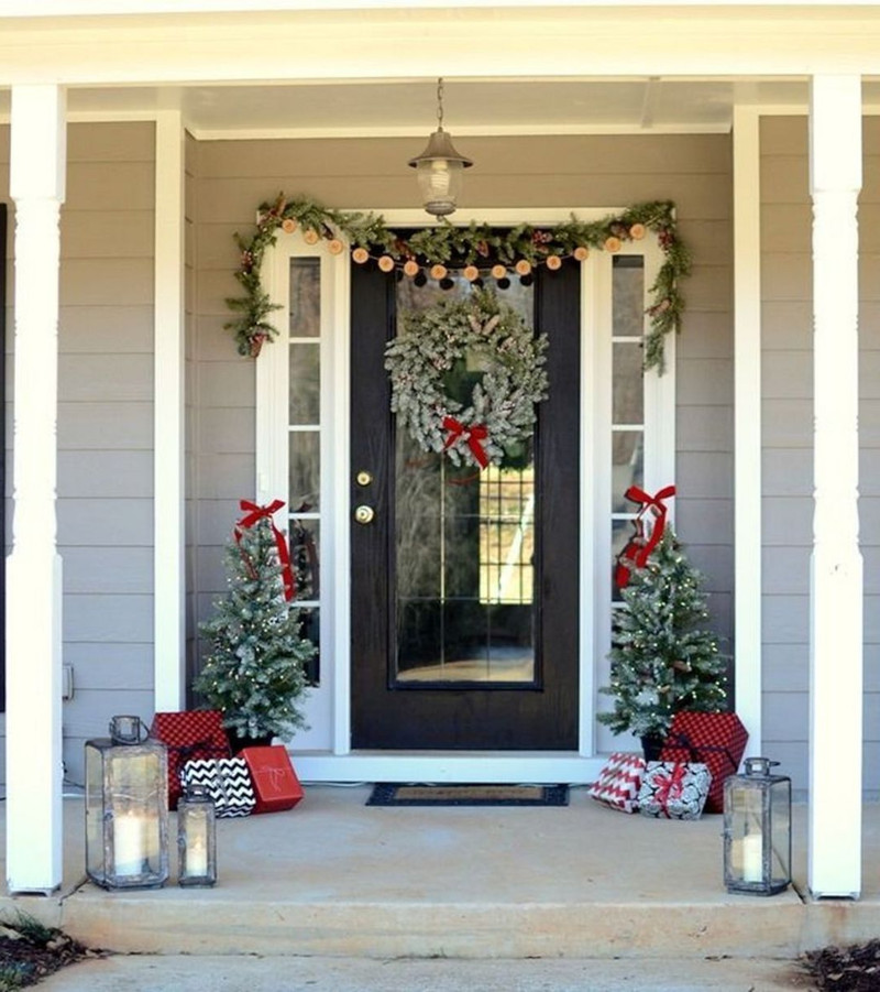 décoration de porte pour noël en gris et rouge sapins pres de la porte cadeaux et bocaux à bougies