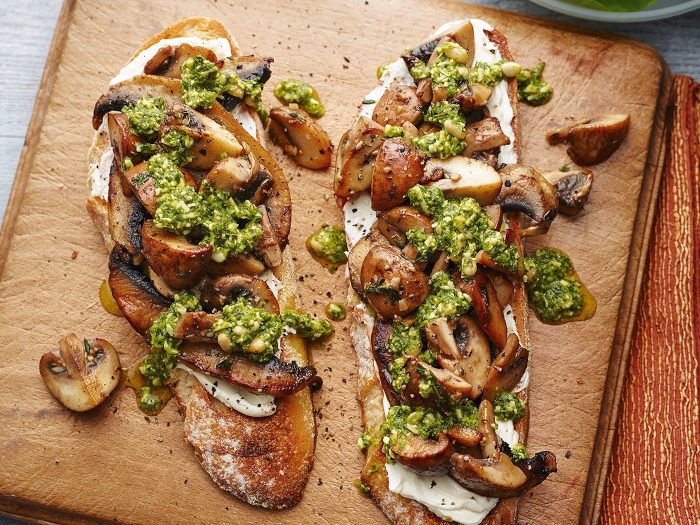 fricassée de champignons avec de la sauce verte servie sur un plateau en bois