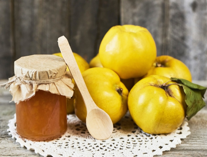 close up of jar of jam and quinces with leaves on wooden rustic