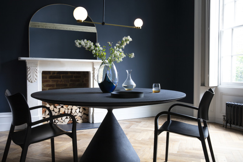salle à manger tendance 2022 mur peint en bleu foncé table originale noire cheminée blanche en contraste