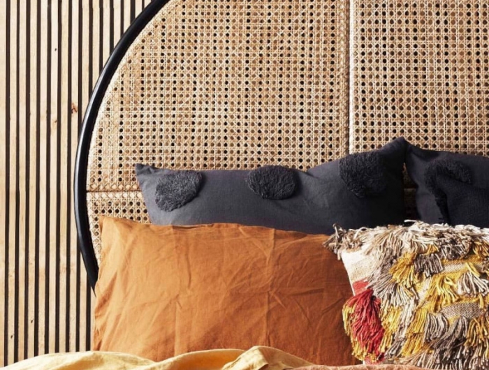 tete de lit moderne en rotin ovale bordure noire mur en bois clair coussins camel et noirs