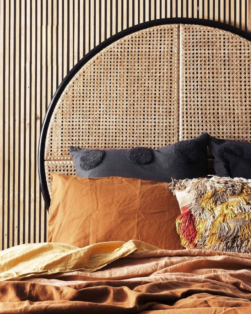 tete de lit moderne en rotin ovale bordure noire mur en bois clair coussins camel et noirs