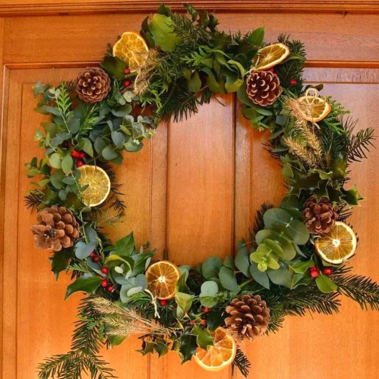 couronne de noel avec des elements decoratifs naturel branches de sapin et des oranges sechees