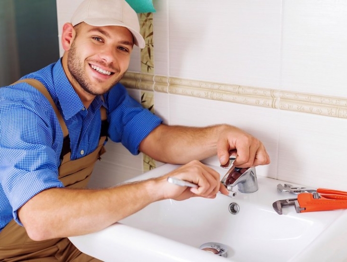 homme chemise bleu casquette beige bricolage dans la salle de bain