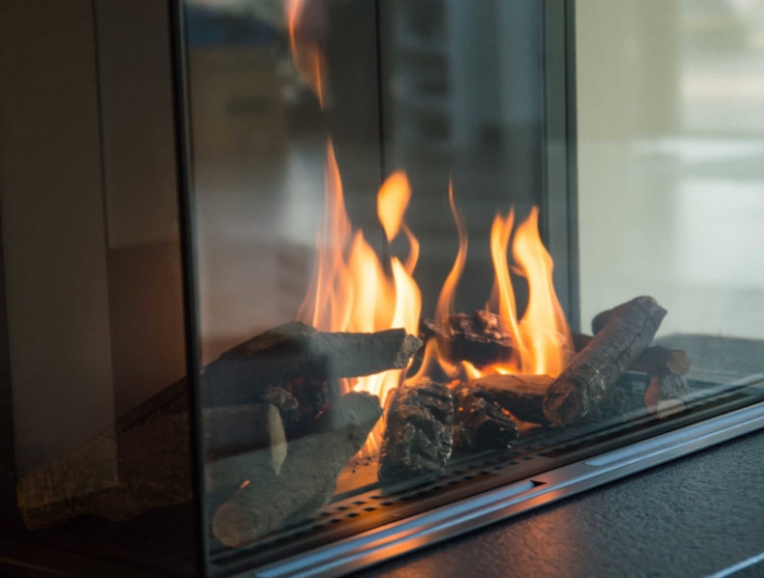 a fire burns in a glass fireplace, radiates heat