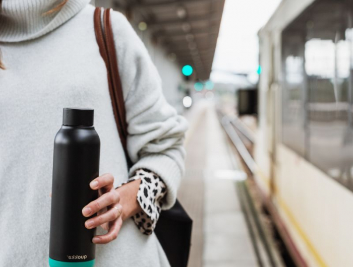 bouteille d eau réutilisable une femme qui attend son train avec une bouteille à la main