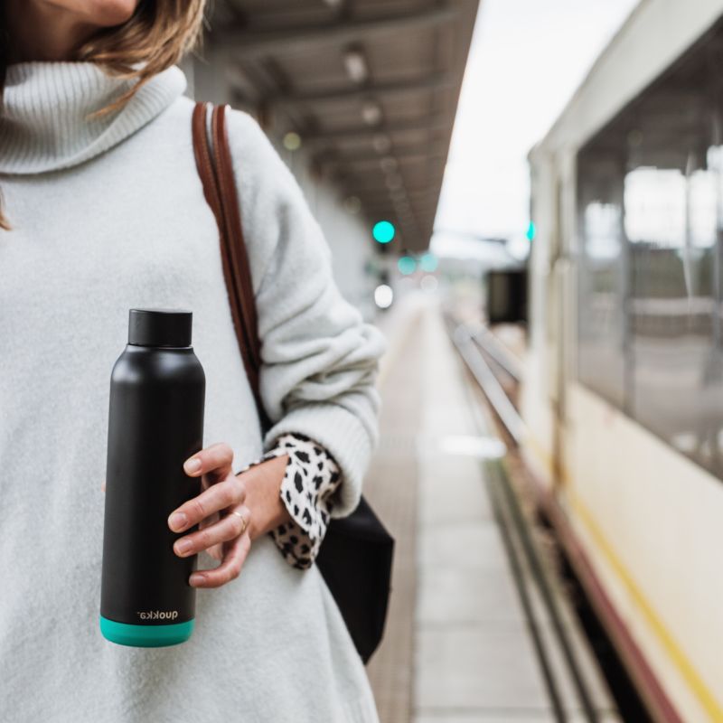 bouteille d eau réutilisable une femme qui attend son train avec une bouteille à la main