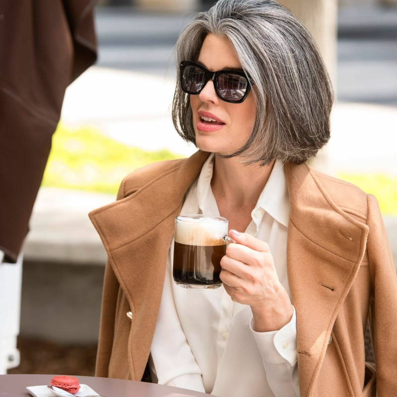 50-year-old woman's haircut with square glasses of salt and pepper Stylish camel coat