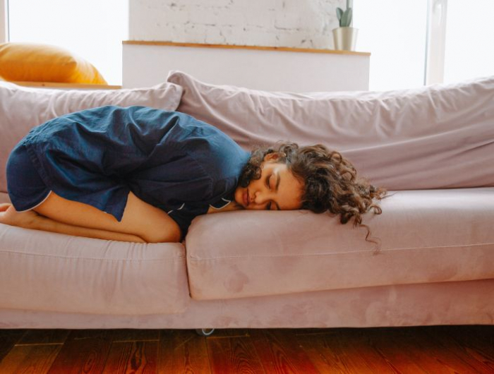 douleur regle une fille blottie sur un canapé à cause du mal au ventre