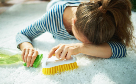 tired woman with cleaning agent and brush laying on carpet