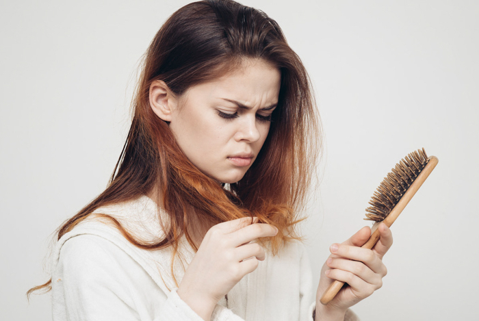 perte cheveux femme une femme mécontente qui peigne ses cheveux