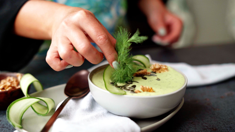 plate of cold avocado soup garnished with dill and pumpkin seeds