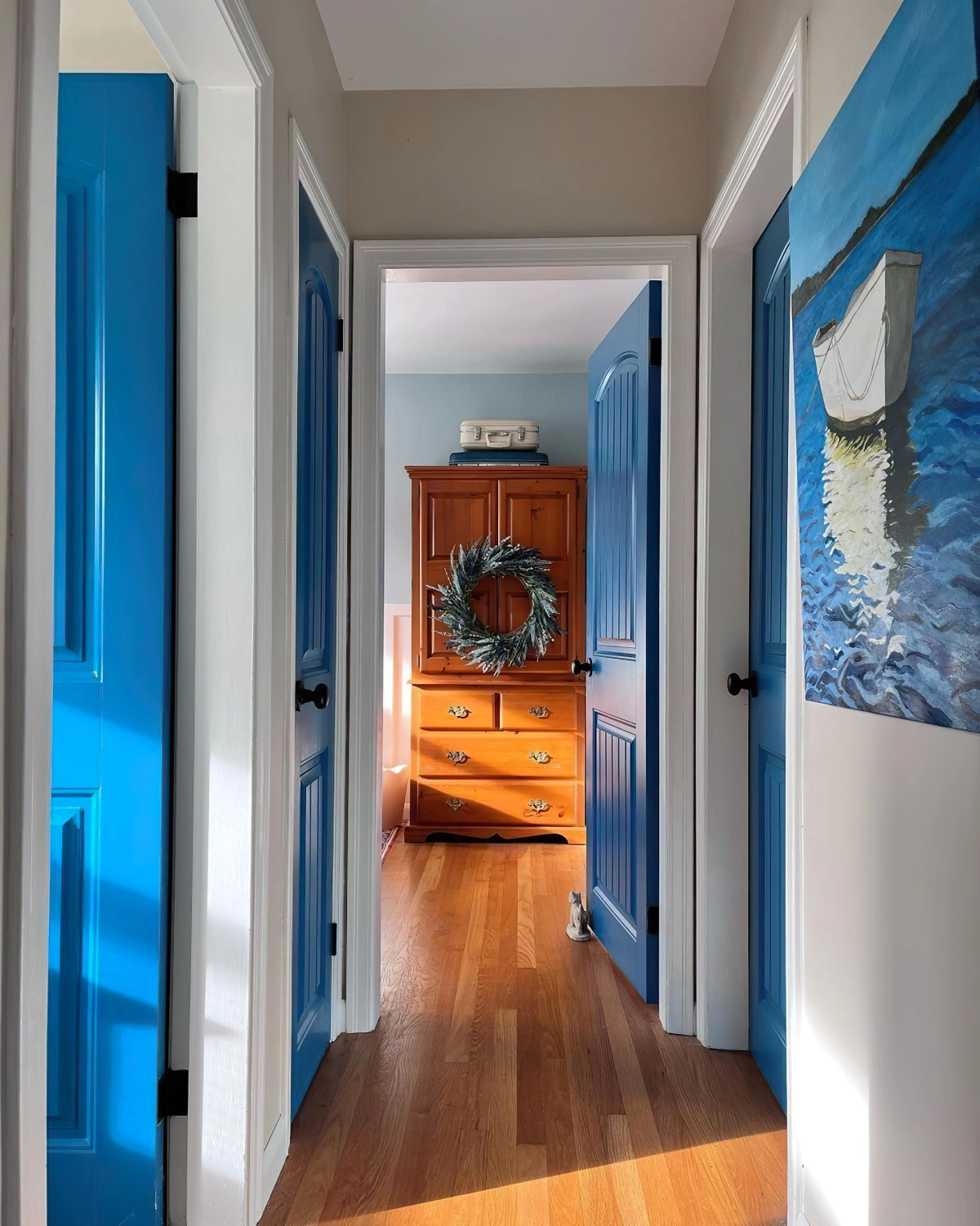 porte peinte en bleu fonce couloir etroit parquet bois plafond blanc