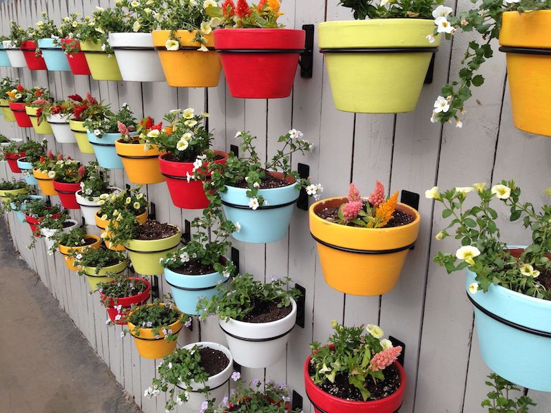 pots de fleurs colorés fixés sur une cloture de jardin bois idee deco mur exterieur jardin